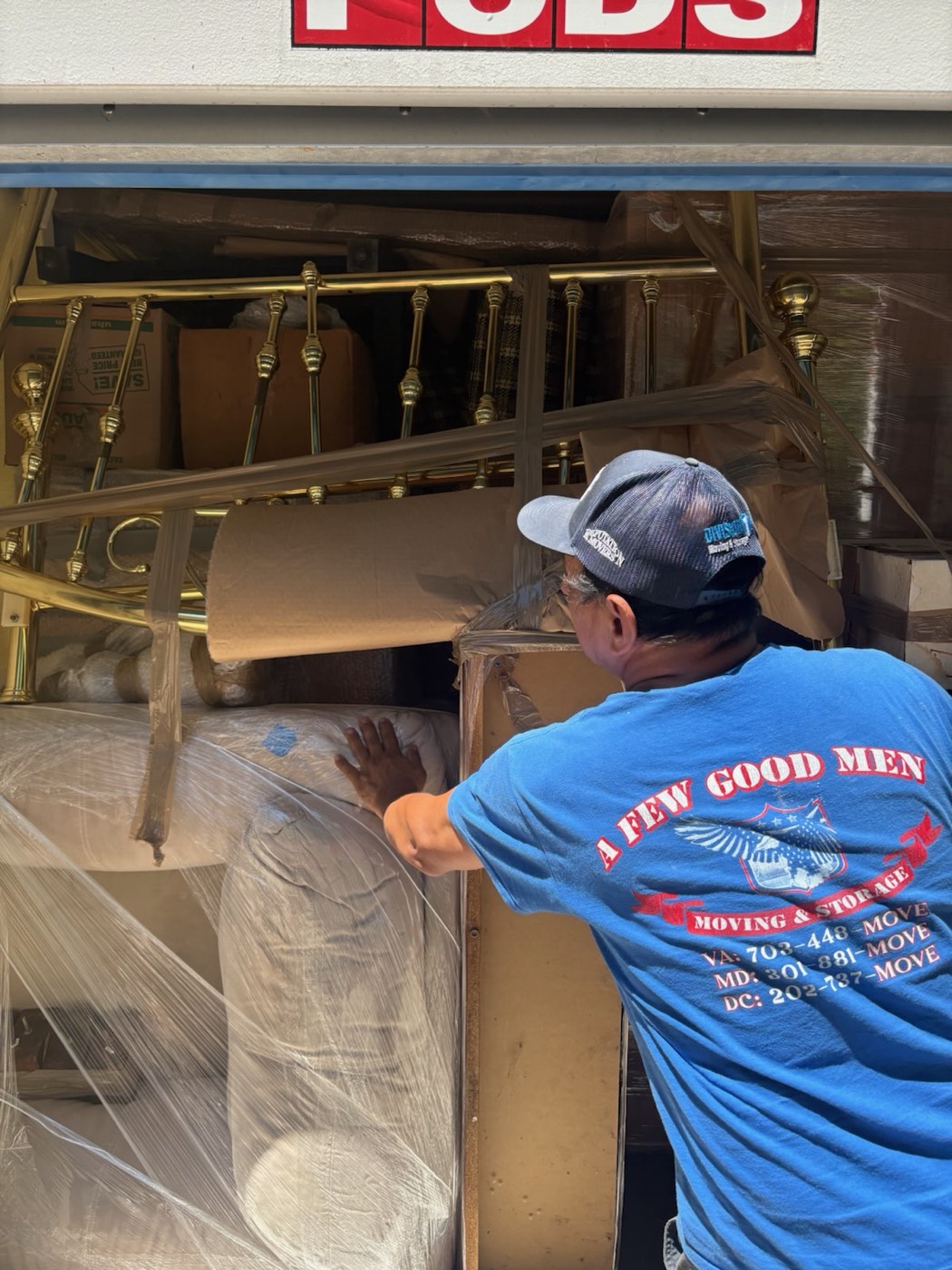 An A Few Good Men mover loading a wrapped household into a portable storage container