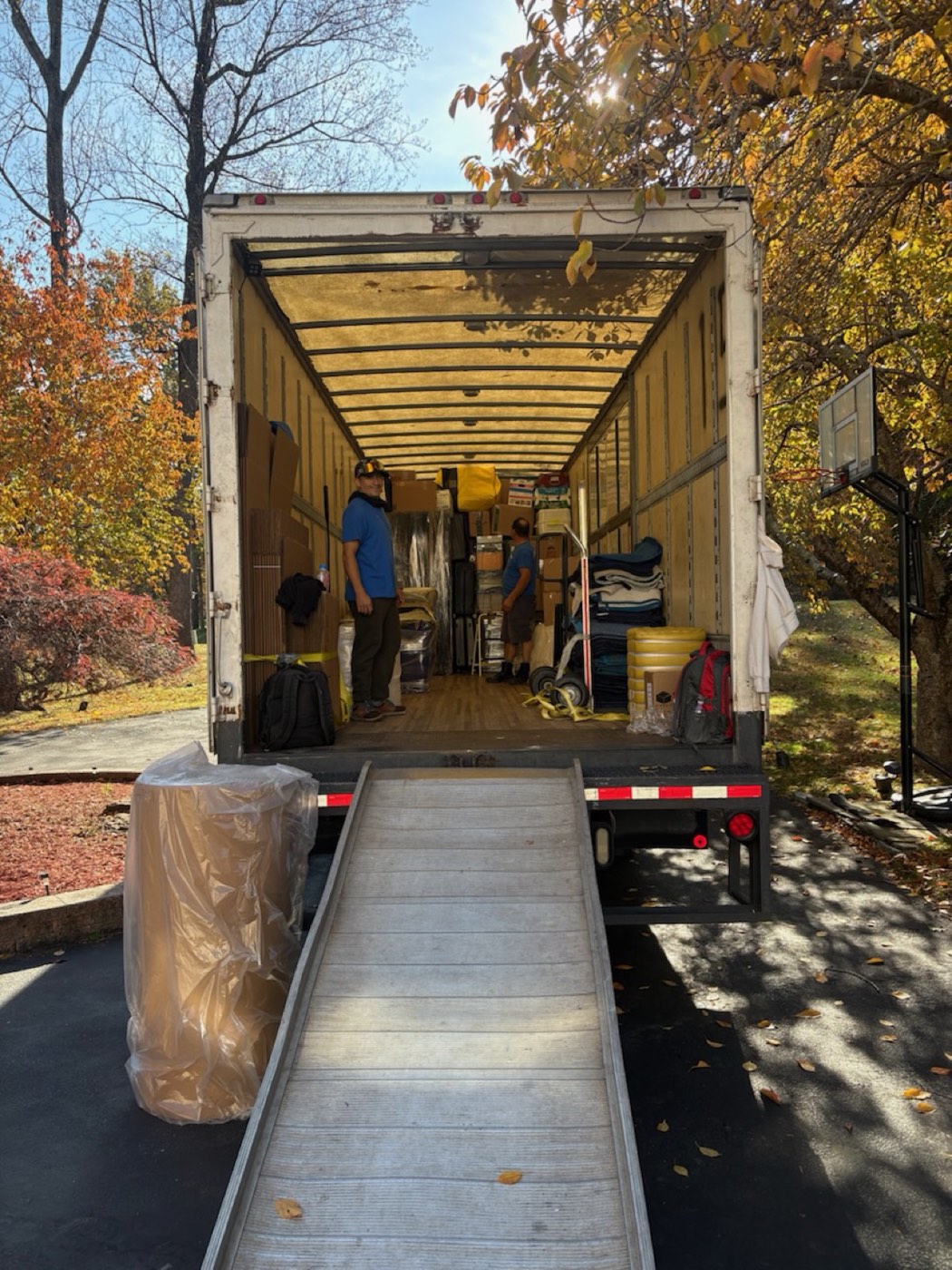 An A Few Good Men box truck backed into a driveway with its loading ramp down and the crew working inside
