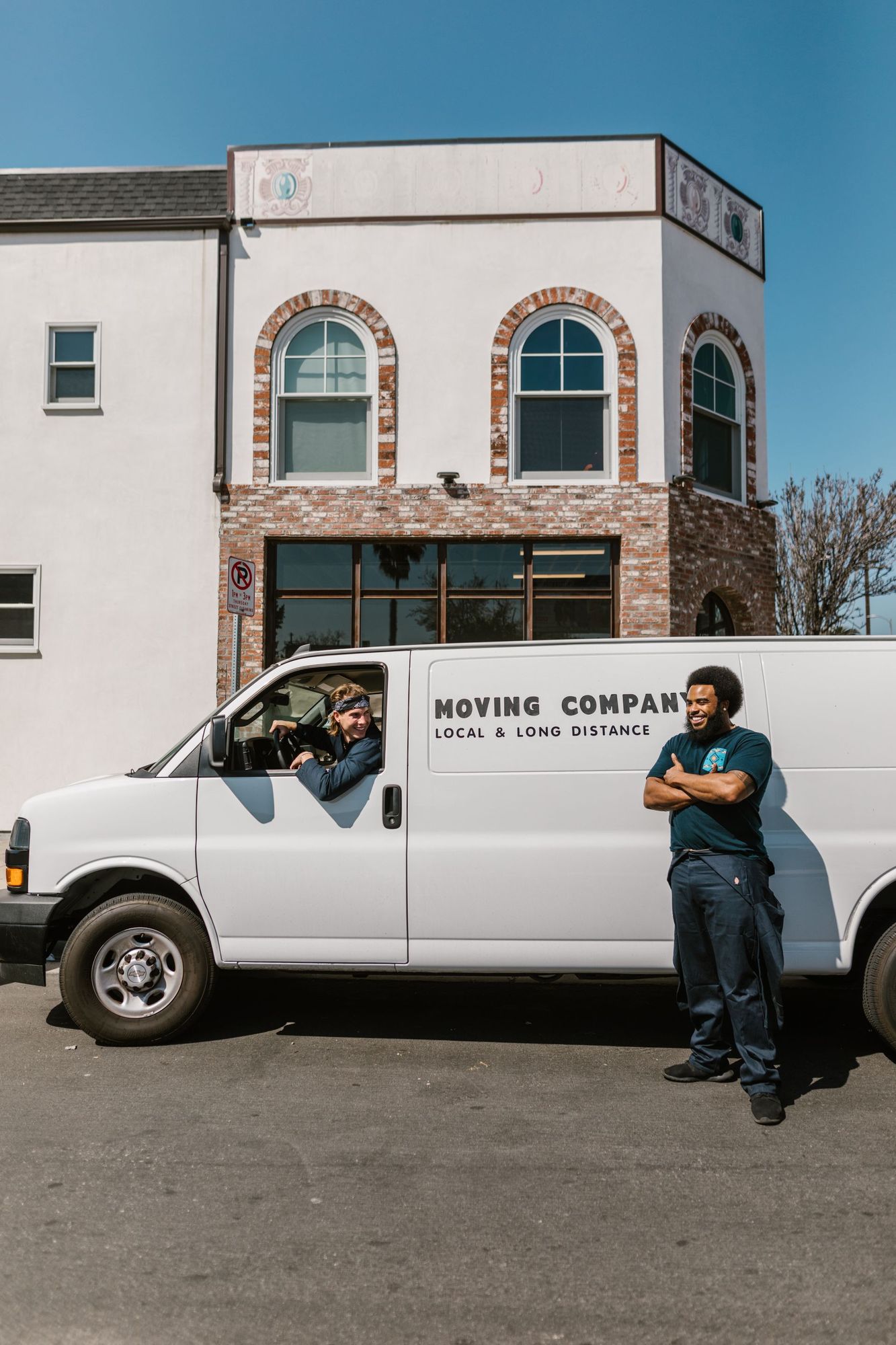 Two movers standing by a company van outside a townhouse, ready for a local job