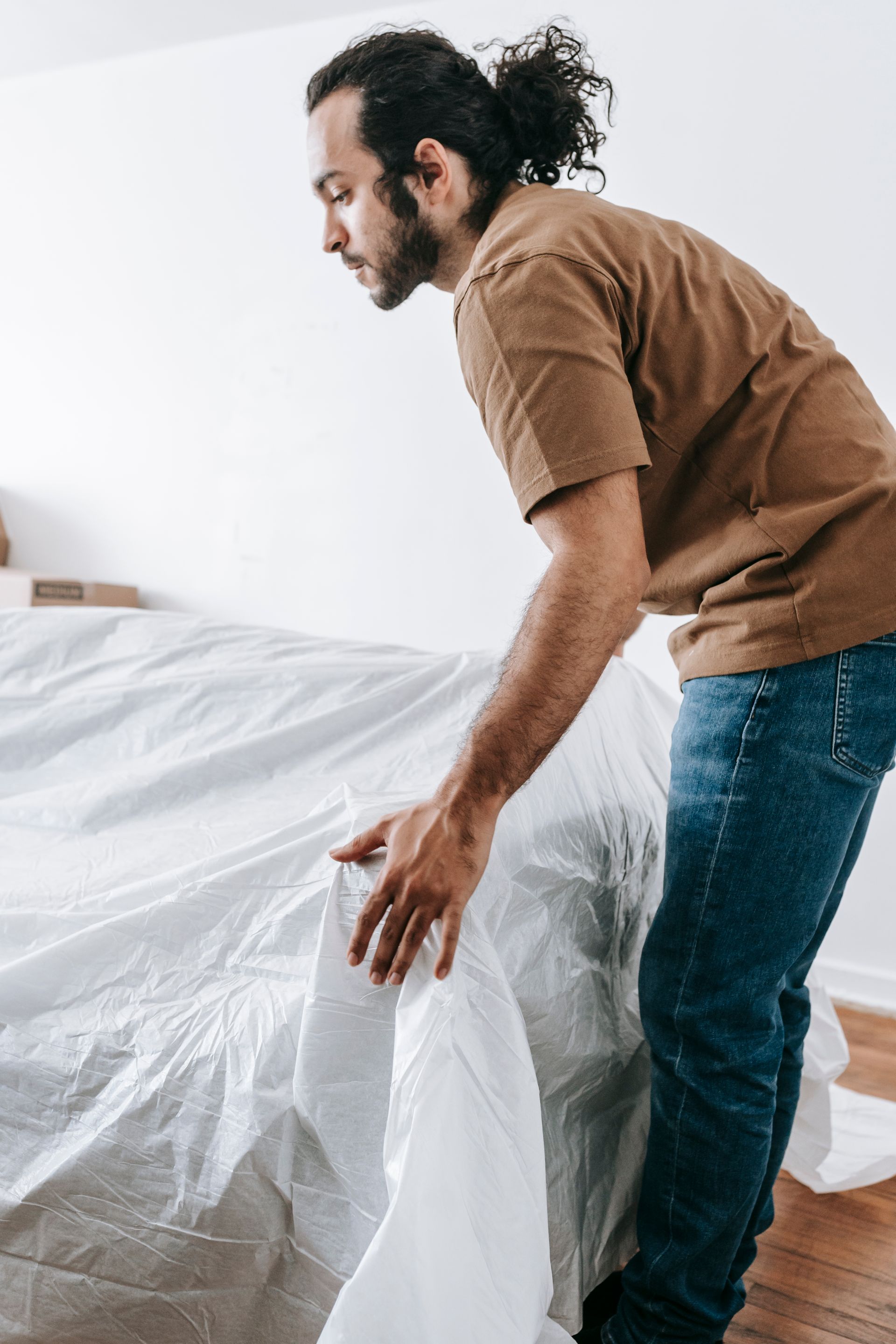 A mover placing a white protective cover over a sofa in preparation for a residential move